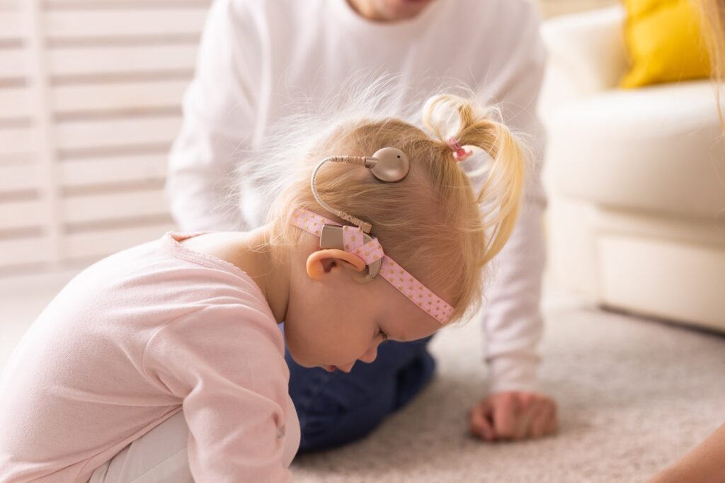 Kid with cochlear implants playing with toys at home. Deafness and medical technology concept